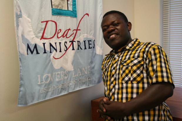 Paul Aseka next to Deaf Ministries banner