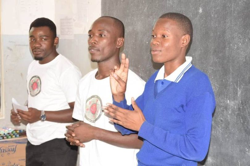 three dark-skinned men using sign language